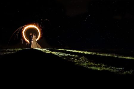 Winter Wedding Photography-53 A winter wedding couple standing on a hill with a sparkler in their hands, beautifully captured by a photographer.