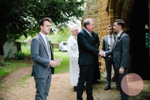 Groom greeting guests outside the Dodford Church