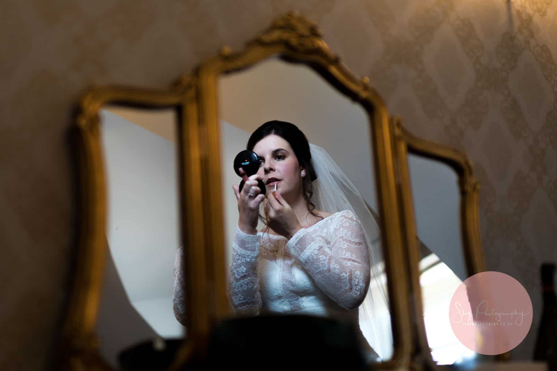 Bride gettting ready in front of a beautiful mirror in the bridal boutique at bassmead barns
