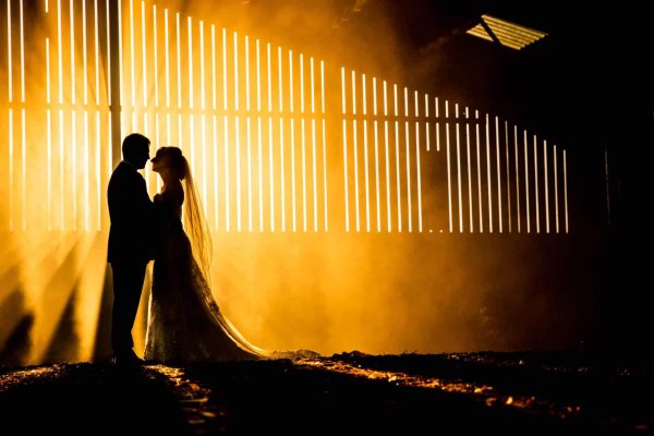 Slider Images-6 Wedding Photographers capture a silhouetted bride and groom in front of a barn in Northamptonshire.