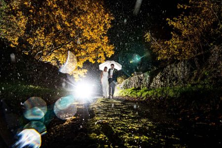 Winter Wedding Photography-23 Wedding photographers capturing a bride and groom under a romantic umbrella in the rain, against the backdrop of Northampton's breathtaking sky.