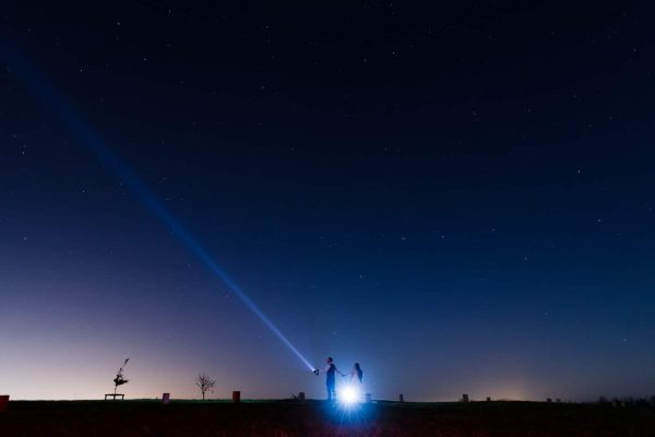Wedding Photography Best of-122 Two people stand under a starry sky with one holding a flashlight that beams upwards, perfectly captured by Dodford Manor Wedding Photographer.