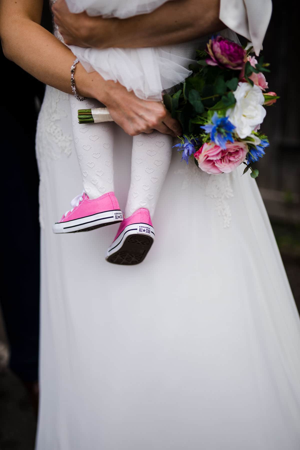 flower girl wearing pink converse shoes matching brides flowers