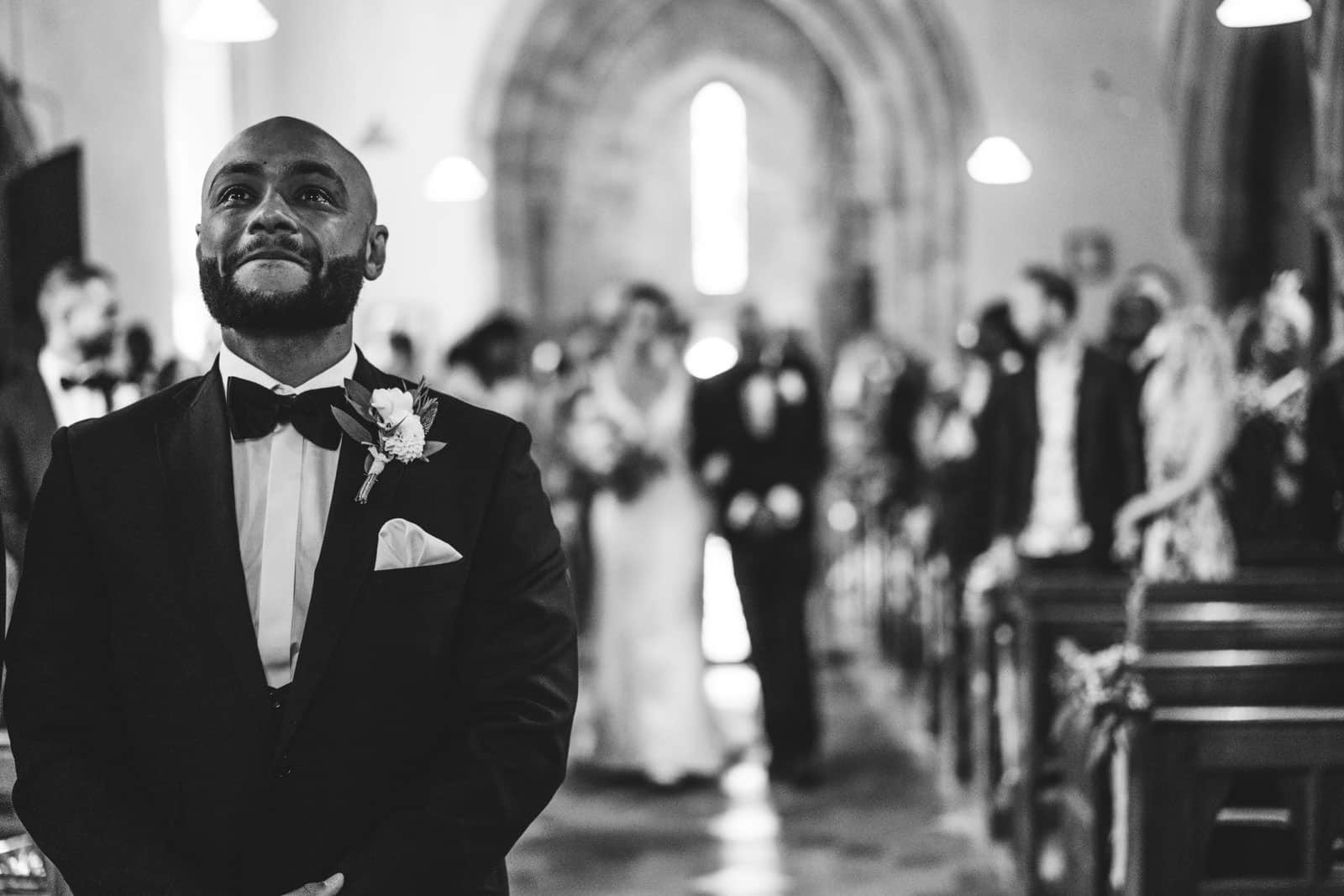 A man in a tuxedo walks down the aisle at a wedding captured by Wedding Photographers Northamptonshire.
