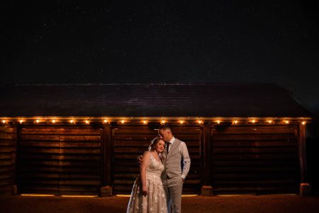 Best of Sky Photography 2021-11 Wedding photographers capturing a bride and groom in front of a charming barn under the enchanting Northampton night sky.