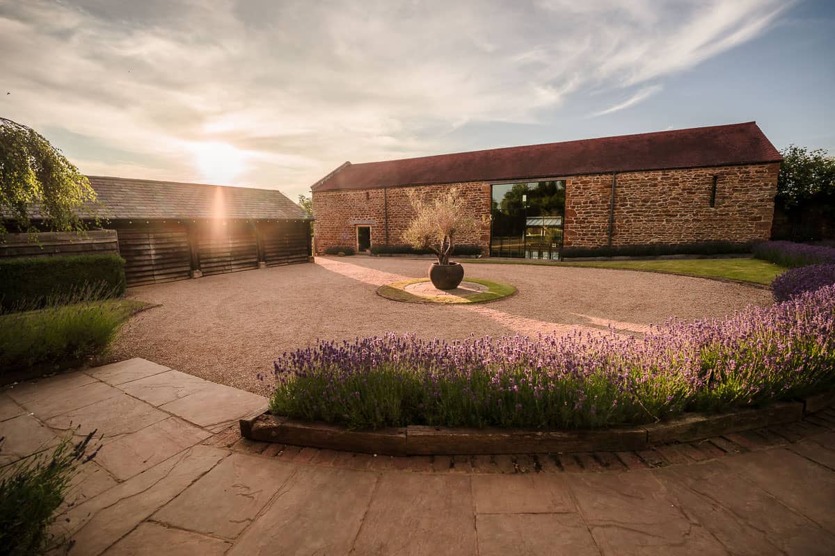Dodford Manor Wedding Venue-5 A picturesque courtyard adorned with lavender showcases a stunning brick building, creating the perfect backdrop for capturing timeless wedding moments at Dodford Manor.