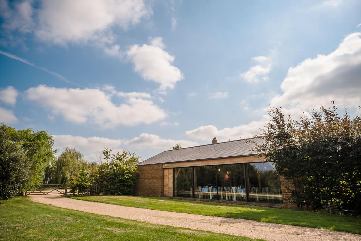 Dodford Manor Wedding Venue-8 Dodford Manor Wedding Photographer: A brick building with a glass door in the middle of a grassy field, perfect for capturing unforgettable moments on your special day.