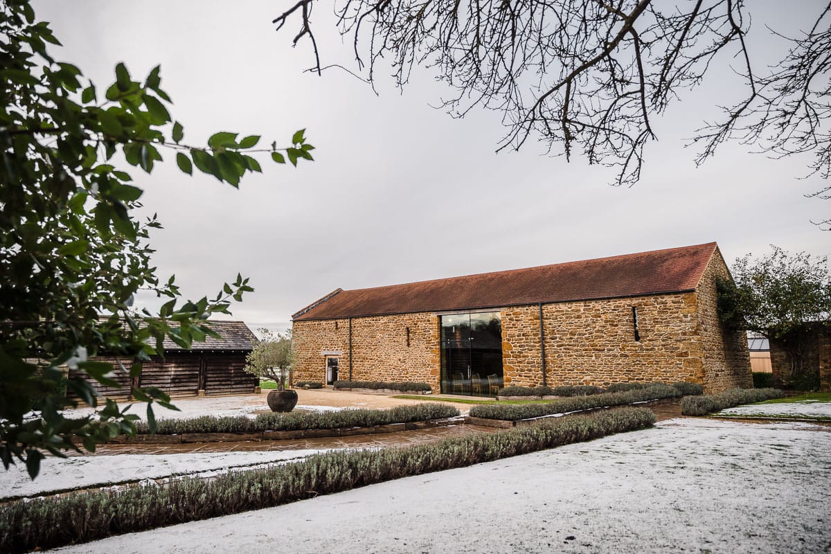 Dodford Manor Wedding Venue-9 A Dodford Manor Wedding Photographer captures stunning moments in a stone barn nestled amidst a snowy field.
