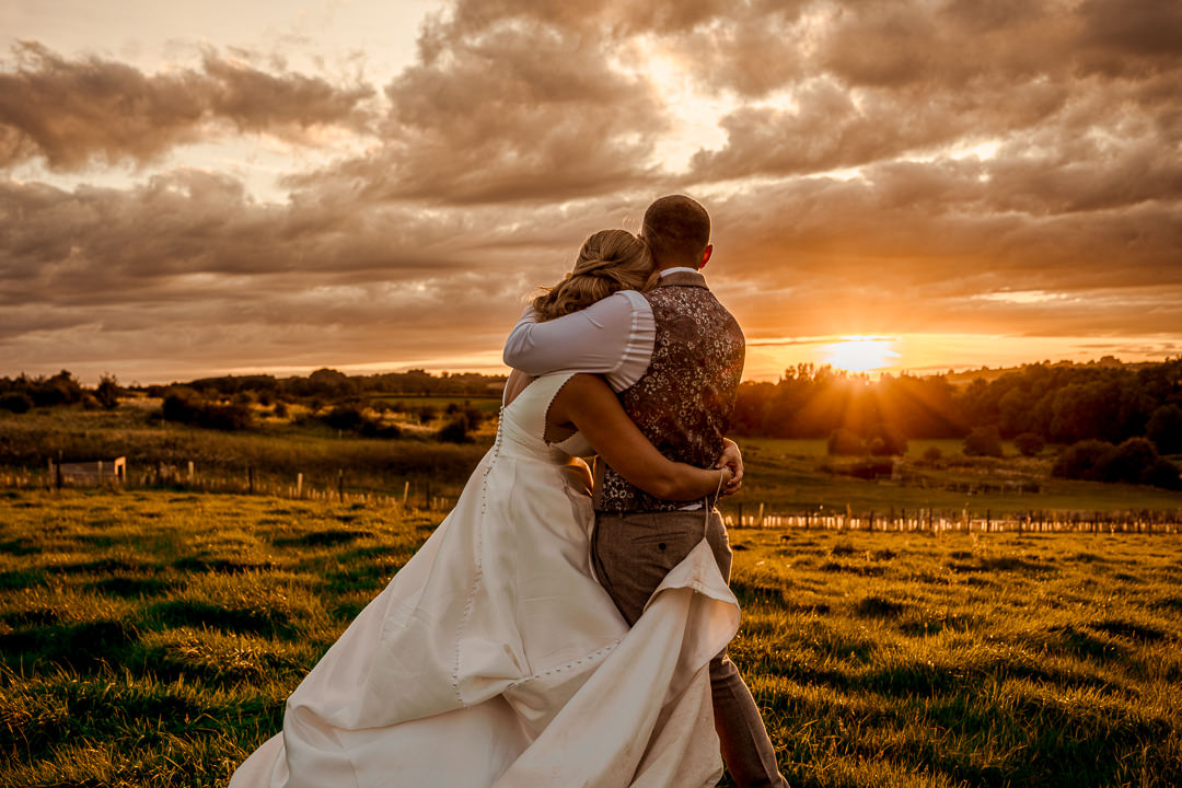 Couple embracing at sunset in a field.