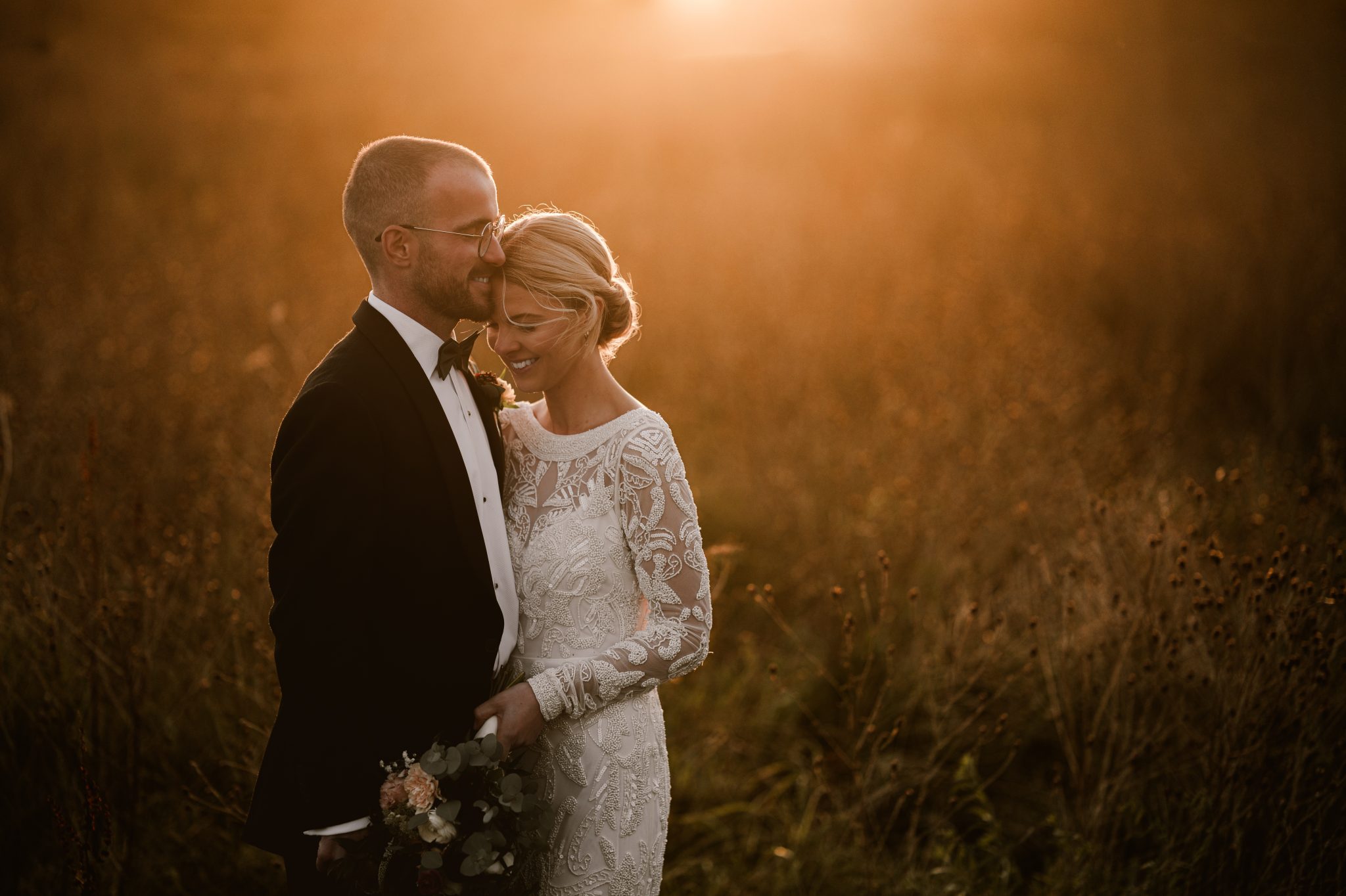 Wedding photographers capturing a bride and groom at sunset in a field in Northampton.