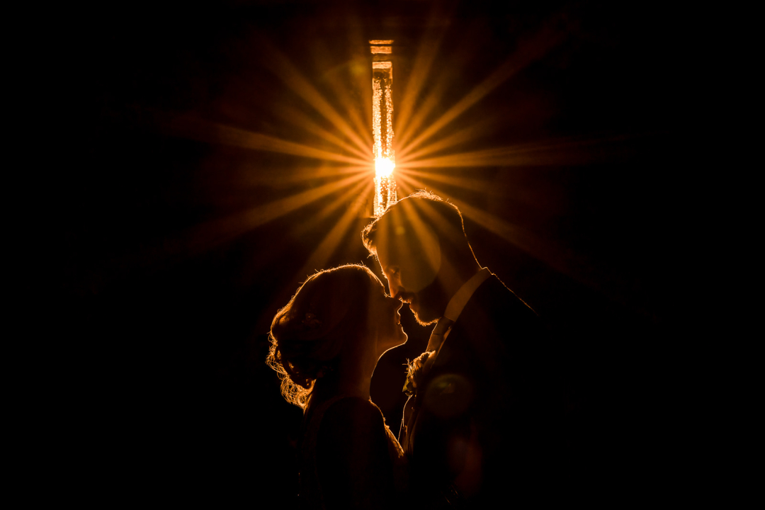Silhouetted couple kissing under starburst light
