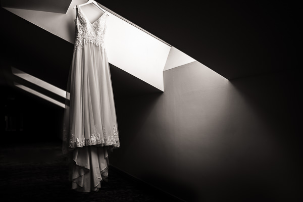 wedding photography portfolio 123 A wedding dress hangs from a skylight, illuminated by natural light streaming through the window, as captured by a talented Warwickshire wedding photographer.