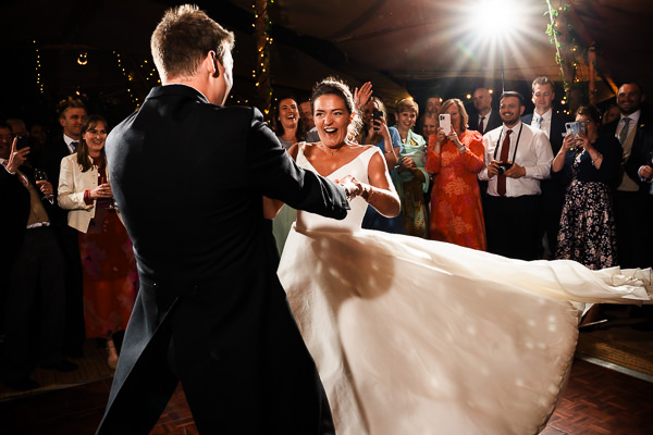 wedding photography portfolio 33 A bride and groom dance energetically at their wedding reception, surrounded by cheering guests.
