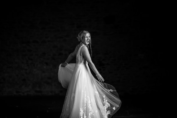 winter low light wedding photographer 29 A woman in a wedding dress spins joyfully, captured beautifully by Milton Keynes Wedding Photographer, set against a dark background.