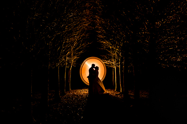 winter low light wedding photographer 3 Silhouette couple kissing under illuminated trees at night.