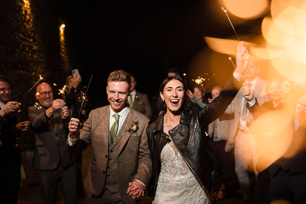 winter low light wedding photographer 40 A couple celebrates with sparklers at a nighttime event, captured brilliantly by a Milton Keynes wedding photographer, amidst smiling friends also holding sparklers and sharing in the joy.