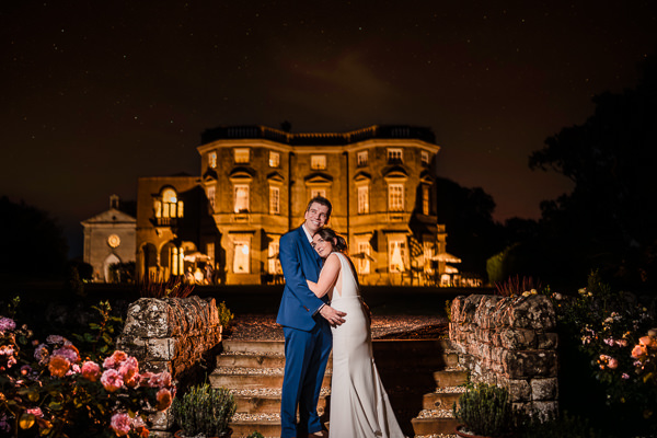 winter low light wedding photographer 44 Couple embracing on steps in front of a grand, illuminated building at night.