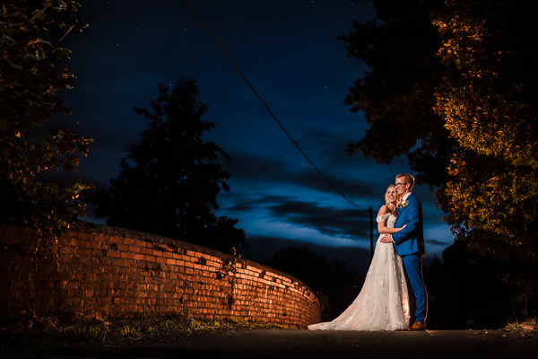 winter low light wedding photographer 51 Couple embraces on a moonlit bridge at night.
