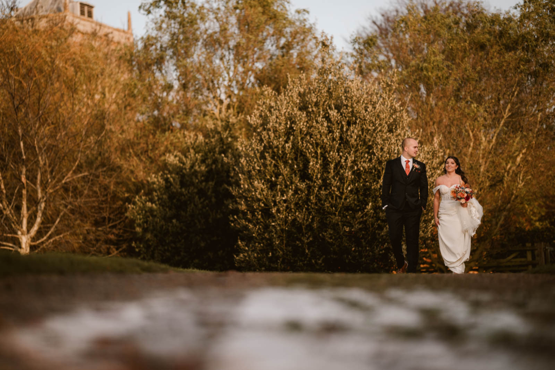 Bride and groom walking in autumn garden