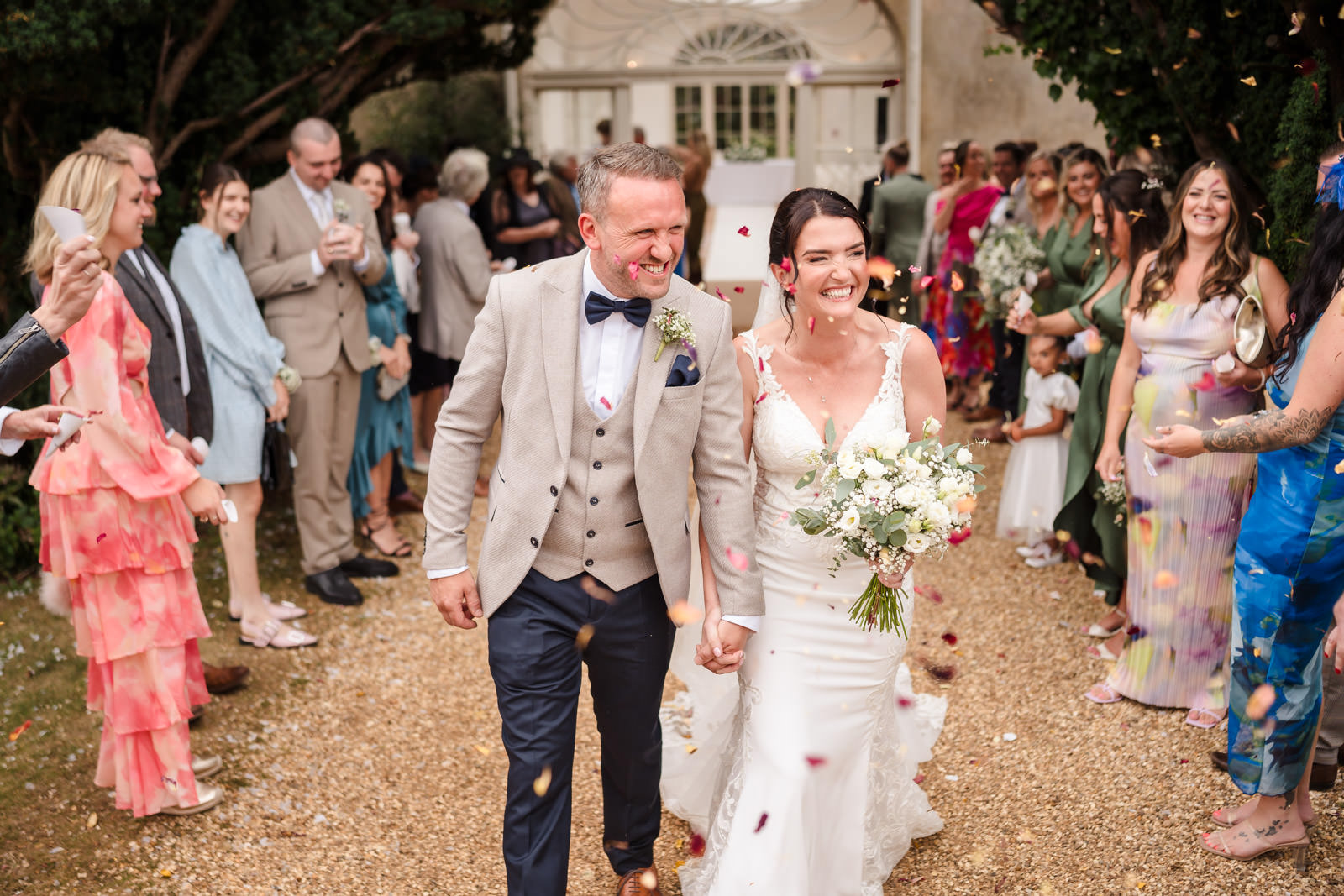 Smiling couple walking surrounded by wedding guests.