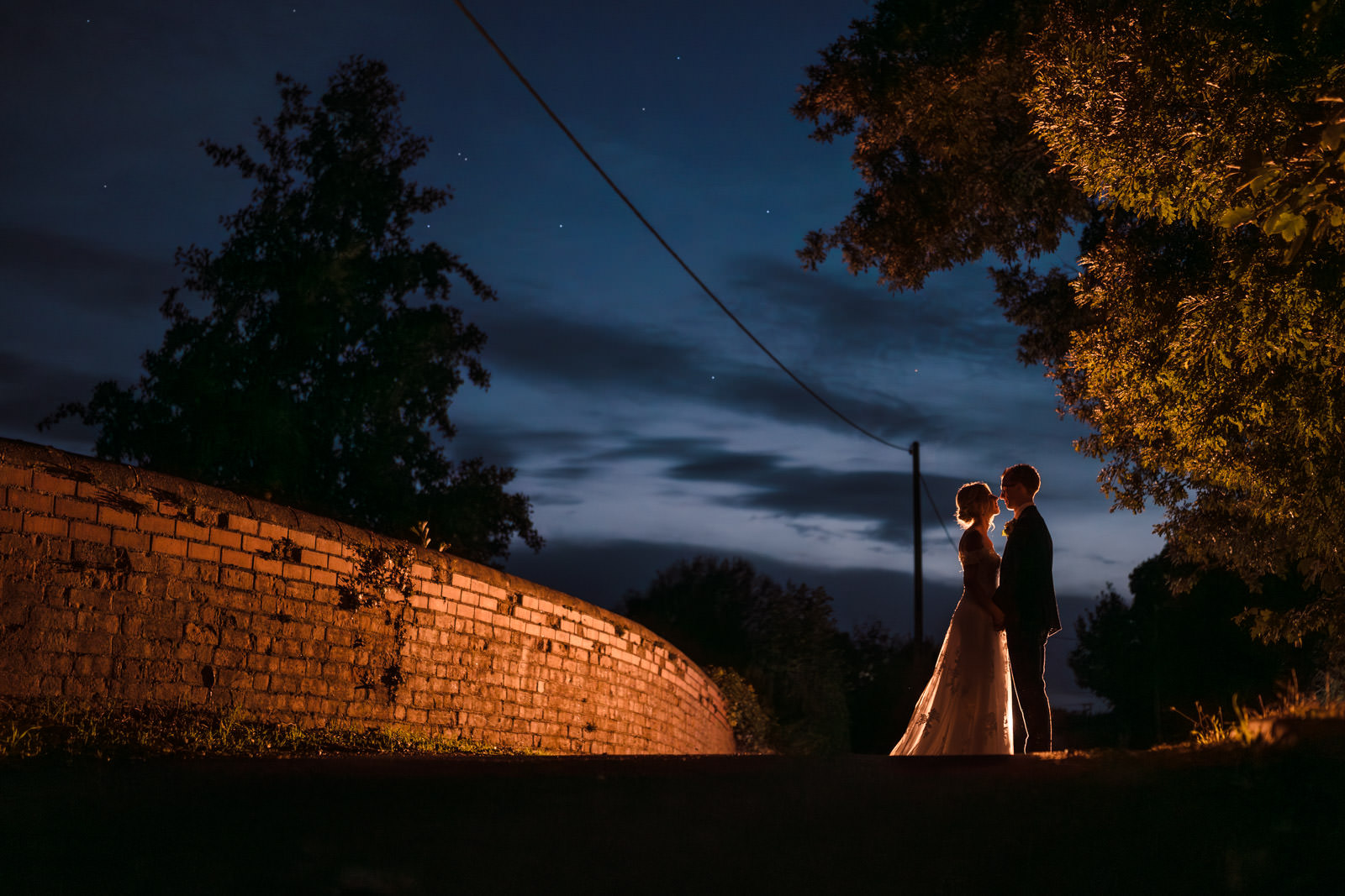 Silhouetted couple kissing under night sky.