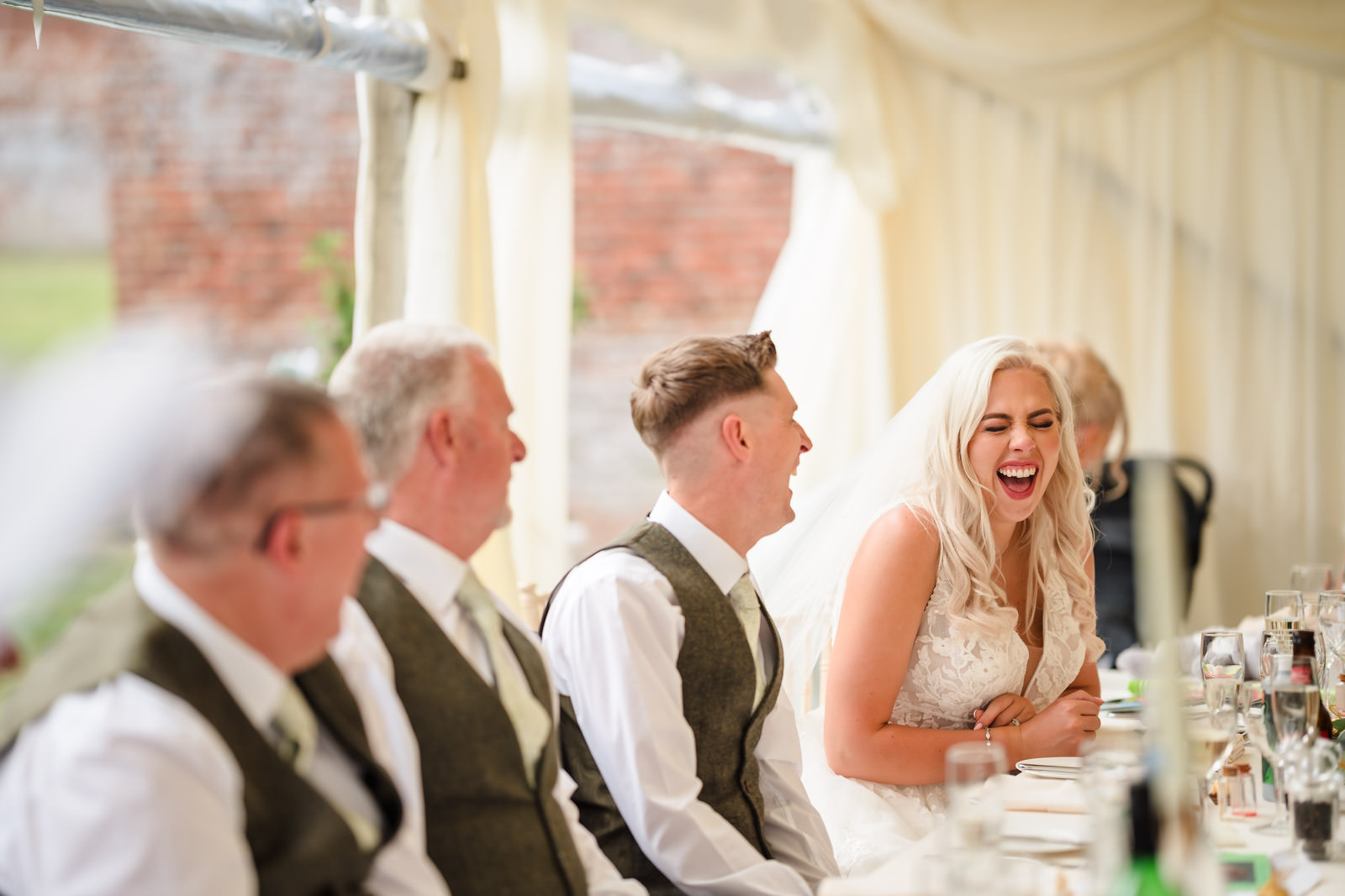 Bride laughing during wedding reception speech