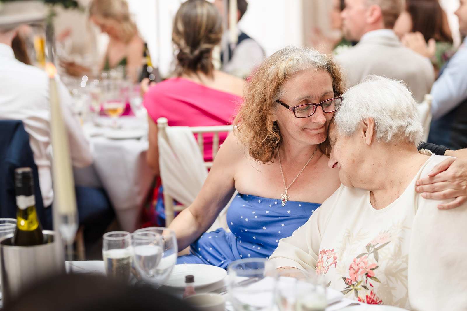 Women hugging at a celebration event, smiling warmly.